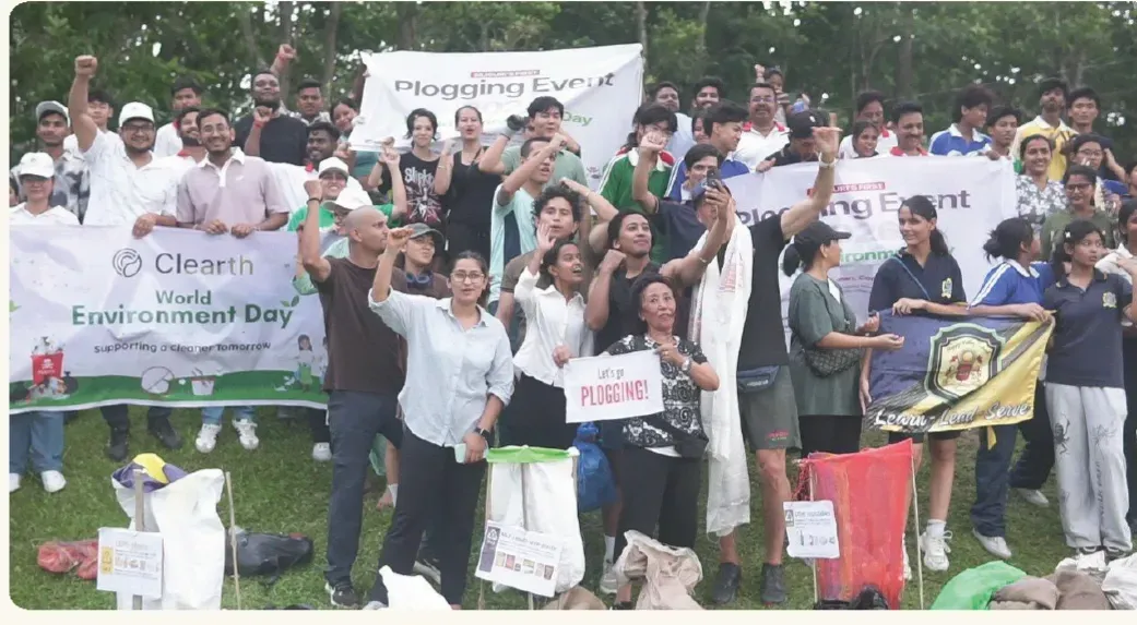 About sixty people with Plogging Event and World Environment Day banners on a field in Siliguri.