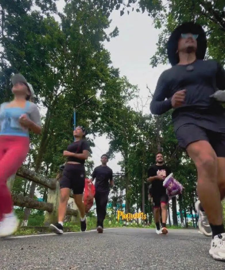 Runners on a tree-lined road, one in front carrying a bag of collected litter.