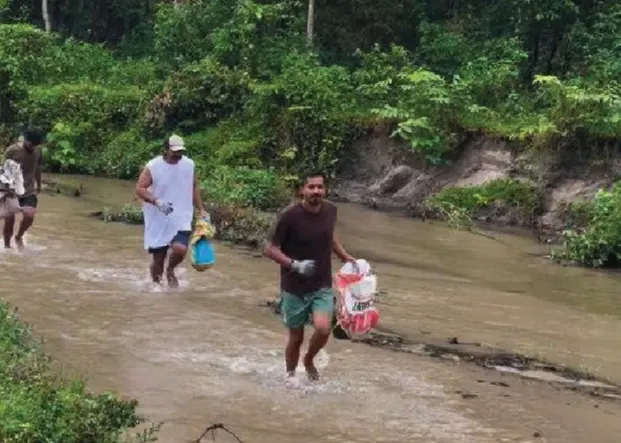 Ploggers wading across a river carrying bags of litter.
